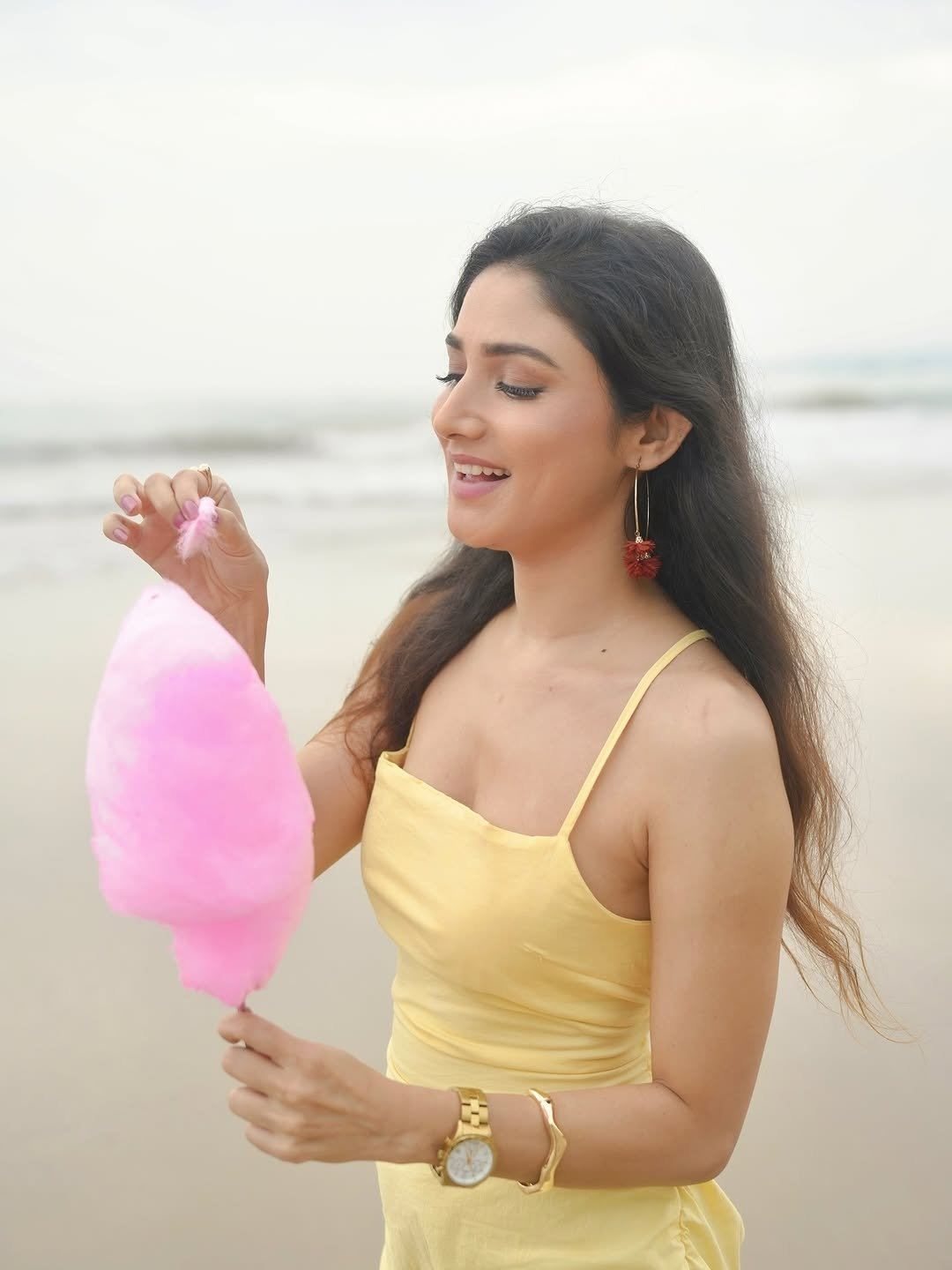 Donal Bisht smiling in yellow dress holding pink cotton candy