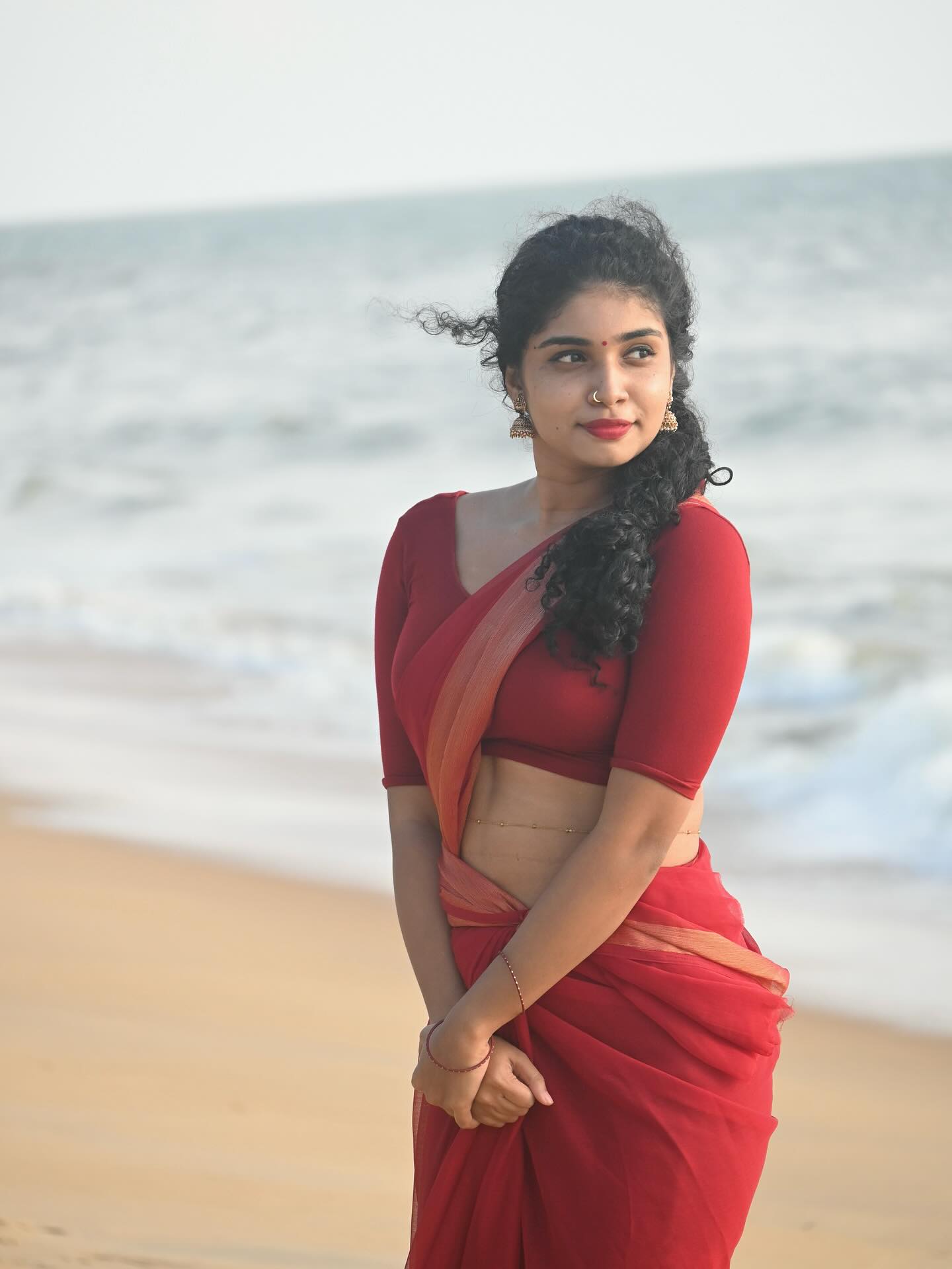 Neeraja Ramesh strikes a graceful, dance-like pose in her red saree.