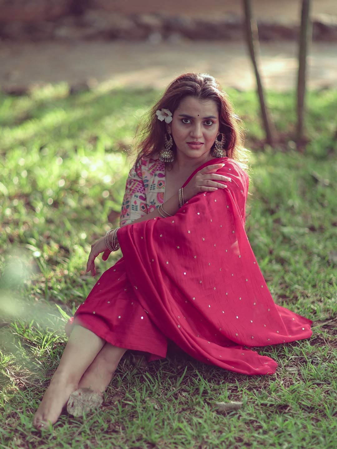 Utkarshica Srivastava looks elegant sitting on the grass in a pink saree.