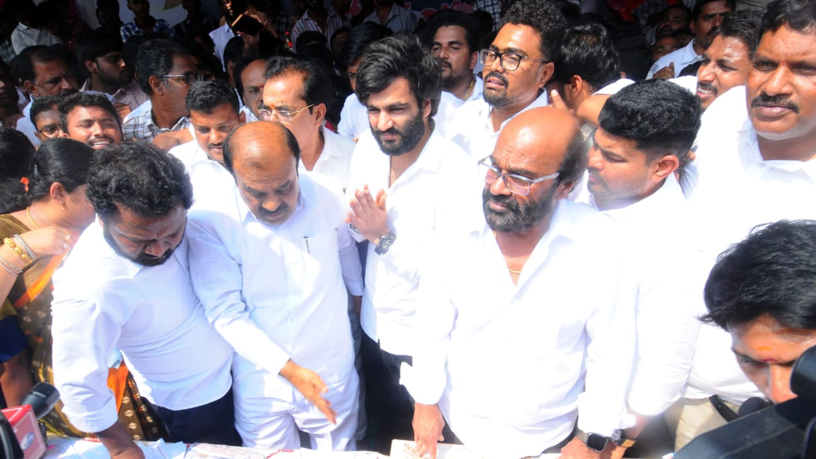 Crowd holding signature banners beside neglected roads — symbolizing YSRCP’s signature drive amid public infrastructure neglect