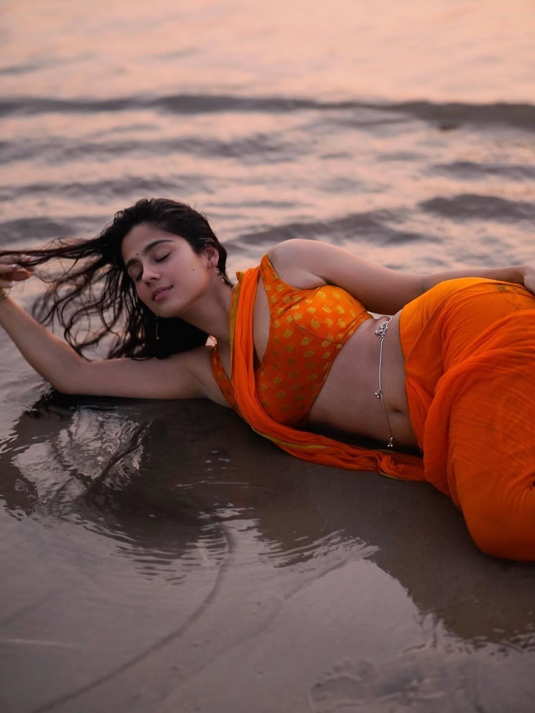 Rose Sardana Lying On Wet Sand In Hot Orange Saree