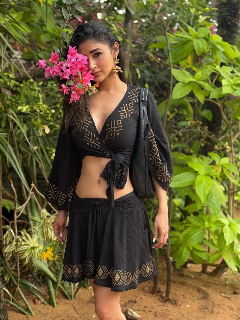 Mouni Roy posing in black outfit near flowers