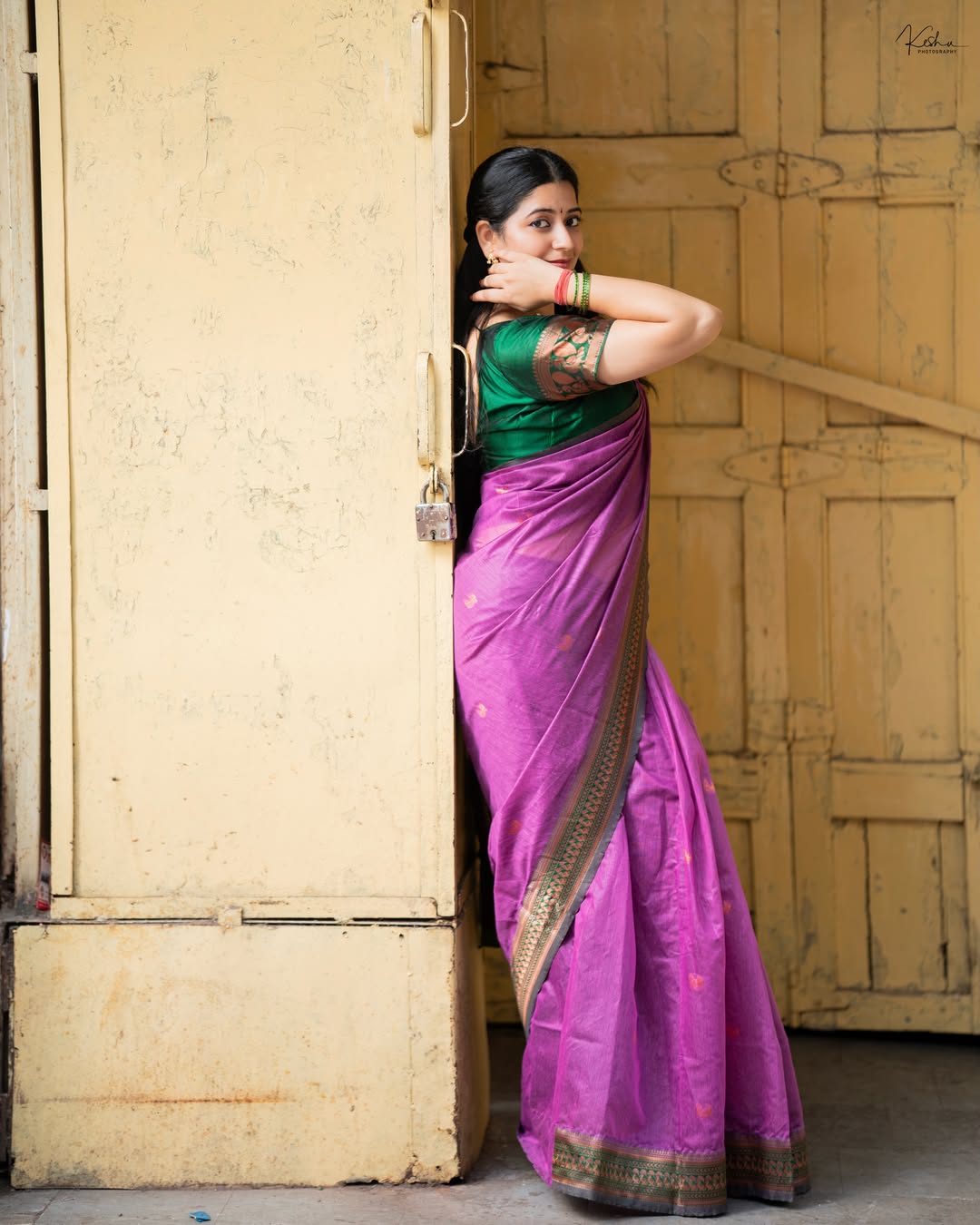 K Sudha Leaning On Wall In Purple Silk Saree