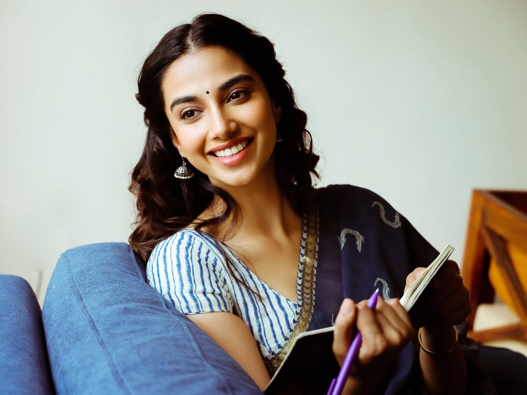 Meenakshi Chaudhary Leaning On Blue Sofa Smiling