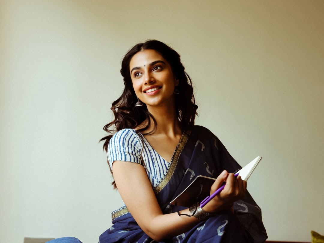 Meenakshi Chaudhary Smiling With Notebook In Hand