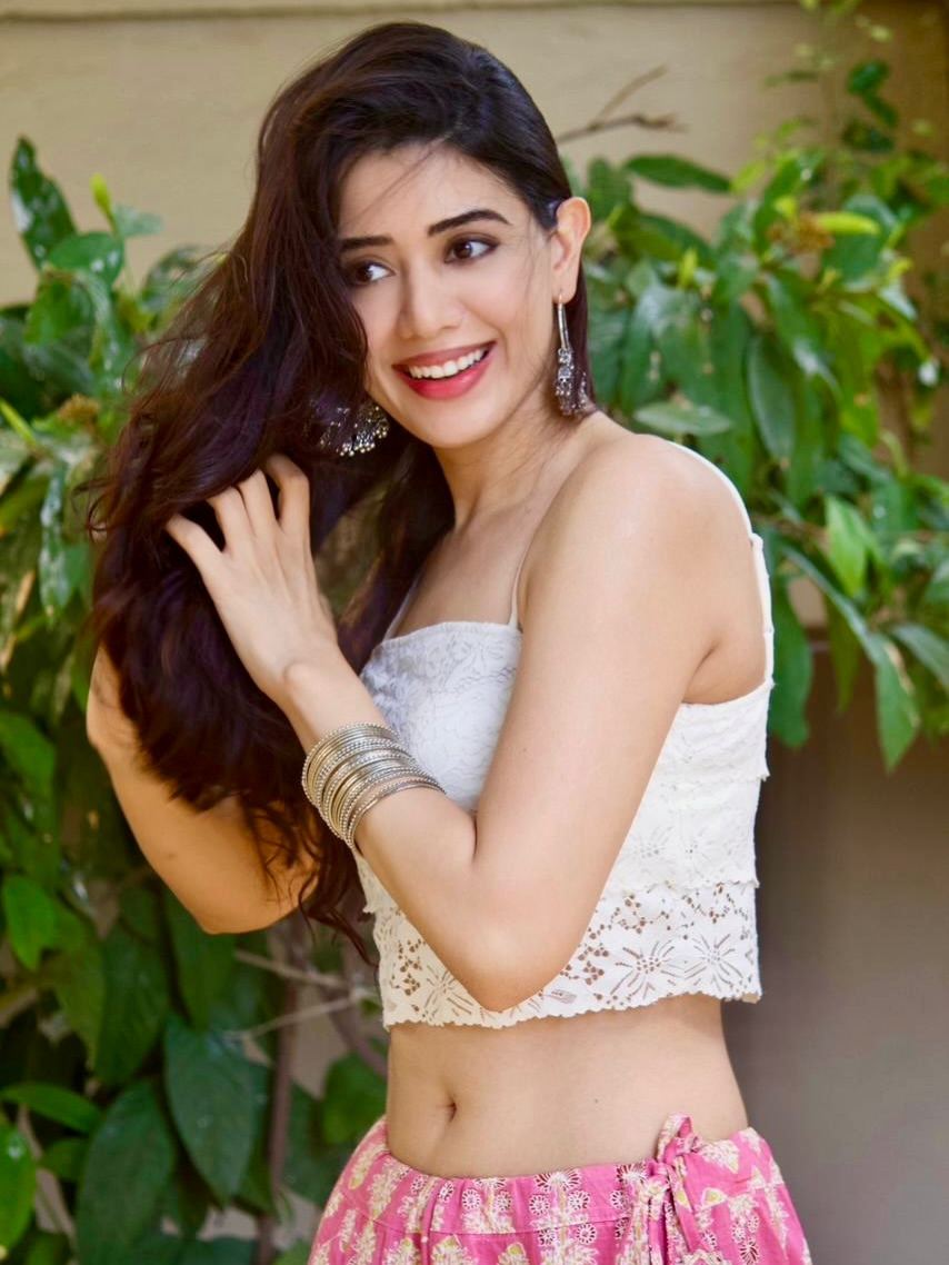 Aarti Chikara Posing Joyfully Against Green Foliage