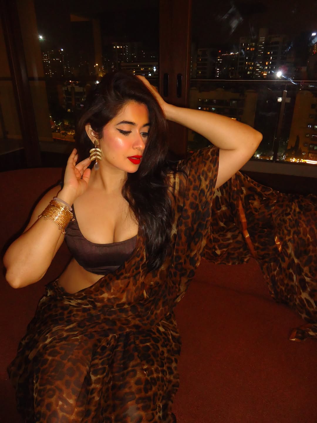 Nikita Sharma Seated On Cozy Crimson Couch