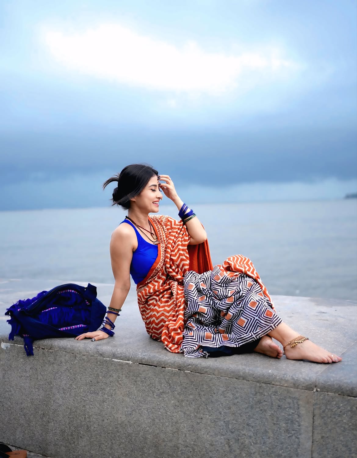 Monami Ghosh Sitting Barefoot On Seafront Ledge
