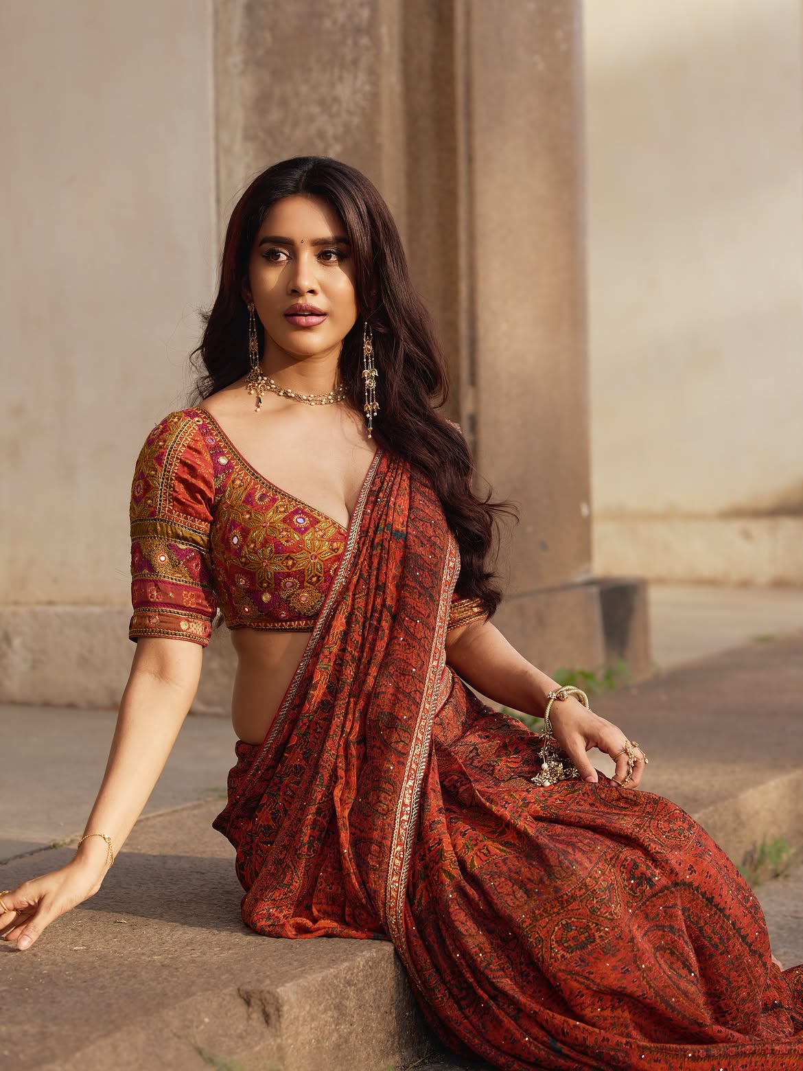 Nabha Natesh Sitting On Stone Floor Looking Away