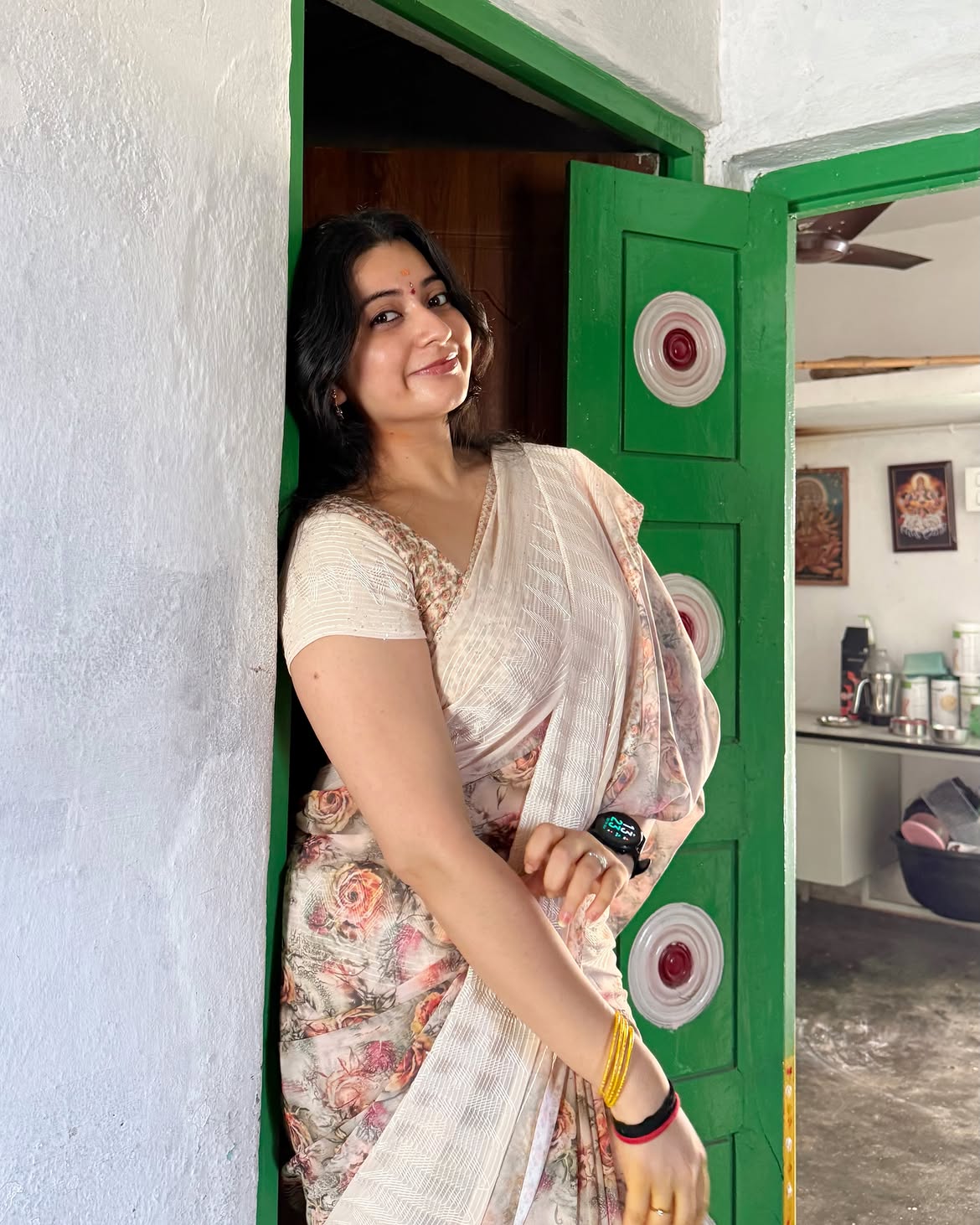K Sudha Relaxes Against Green Door In Sari Drape